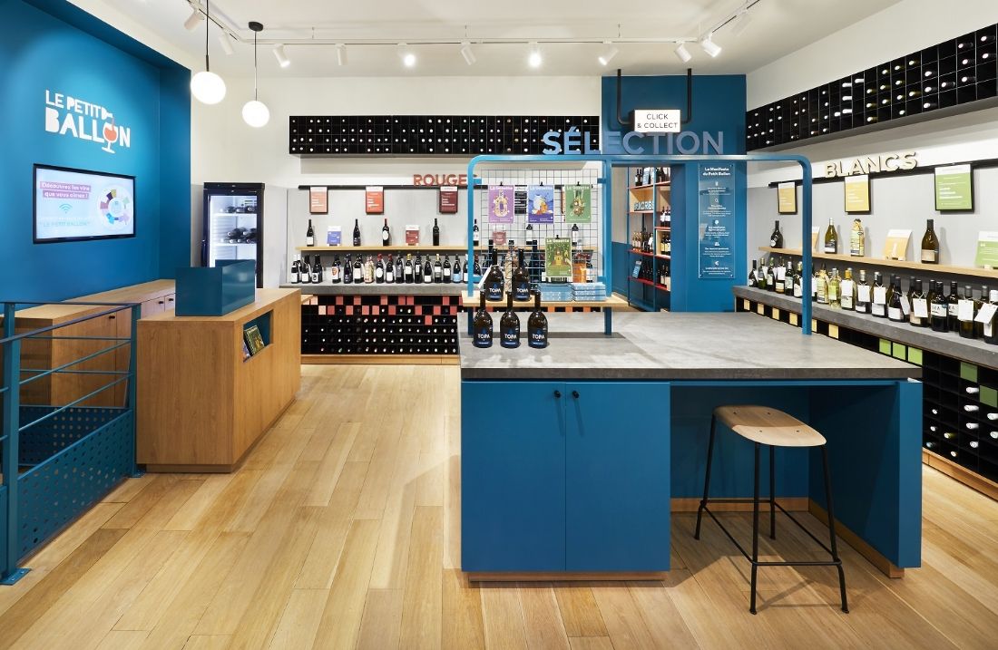 Inside a Le Petit Ballon cellar: shelves of reds and whites around a blue central island